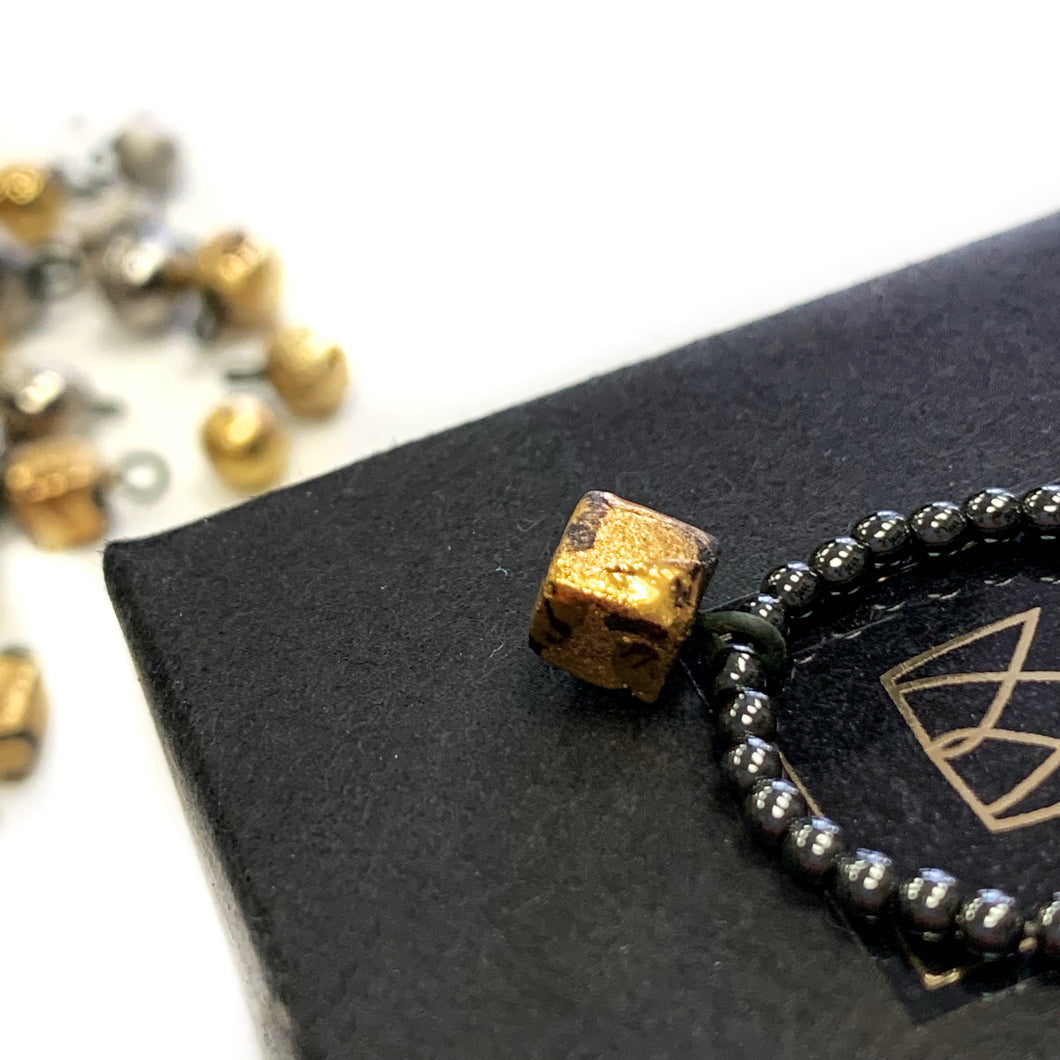 Hematite beads ring with a gold plated black porcelain cube  
